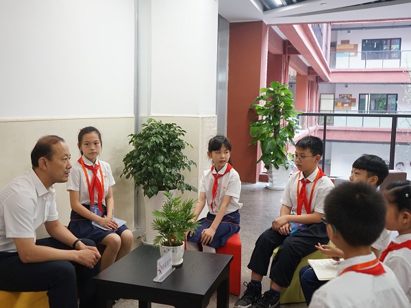 九龙坡区第一实验小学校长何军亲切地与校园小记者交谈。.jpg